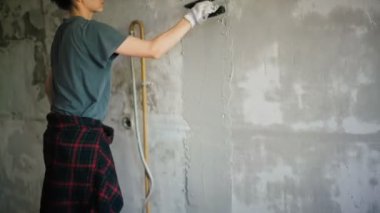 Profesyonel bir tamirci duvara spatulayla sıva yapıştırır..