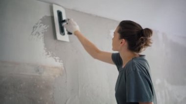 Profesyonel bir tamirci duvara spatulayla sıva yapıştırır..