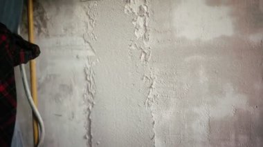 Profesyonel bir tamirci duvara spatulayla sıva yapıştırır..