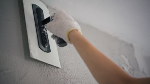 Close-up shot of a professional repairman repairing the wall with a putty knife — Stock Video