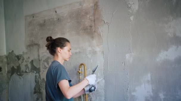 Uma reparadora profissional coloca um gesso na parede com uma espátula. — Vídeo de Stock