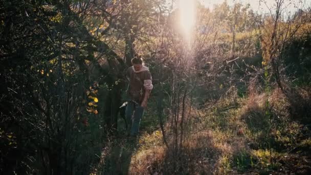 큰 썰매끄는 개를 끈에 매고 숲 속을 걷고 있는 한 젊은 여자. — 비디오