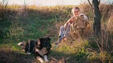 Genç yetişkin bir kadın köpeğiyle yürürken telefonunu kullanıyor.