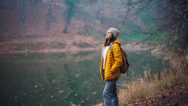 A young adult woman standing at the forest lake and taking a deep breath. — Stock Video