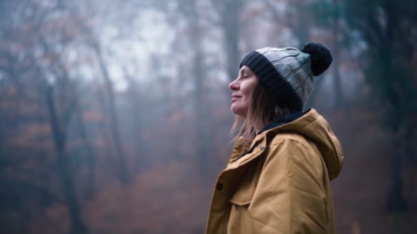 Una donna si trova sulla riva di un lago forestale e gode della vista — Video Stock