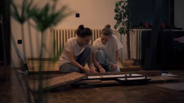Κινηματογραφική φωτογραφία νεαρού λεσβιακού ζευγαριού να συναρμολογεί έπιπλα στο νέο τους σπίτι — Αρχείο Βίντεο