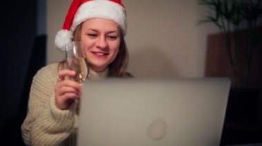 Noel Baba şapkalı bir kadın arkadaşlarıyla laptoptan video görüşmesi yapıyor.