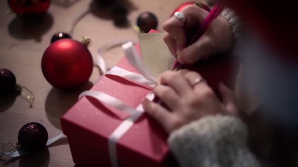 Närbild skott av kvinnliga händer skriva ett gratulerande meddelande på gåva taggen. — Stockvideo
