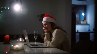 Noel Baba şapkalı bir kadın arkadaşlarıyla laptoptan video görüşmesi yapıyor.