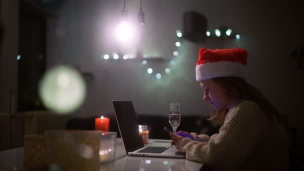 Noel şapkalı güzel bir kadın telefon ekranına bakıyor. — Stok video