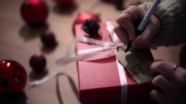 Kadın ellerinin hediye etiketine tebrik mesajı yazarken yakın plan çekimleri..