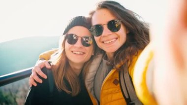 Güneş gözlüklü iki genç kadın selfie çekiyor.