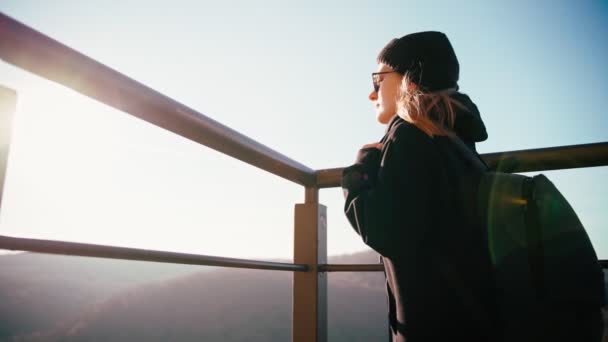 Una joven con una mochila de pie en la plataforma de observación disfrutando de la vista superior — Vídeo de stock
