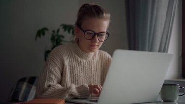 Dizüstü bilgisayarda yazan gözlüklü neşeli bir genç kız.