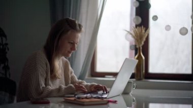 Dizüstü bilgisayarında yazan neşeli sarışın bir kız.