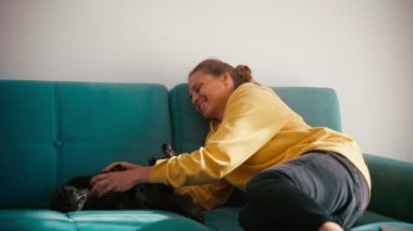 A young adult cheerful woman playing with her cute cat