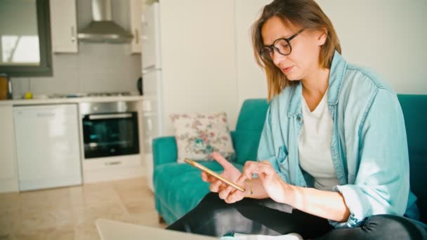 Young adult woman wearing glasses typing a message on her smartphone while — Stok video