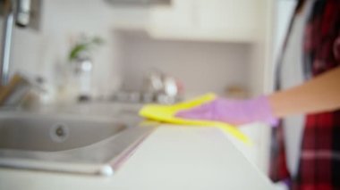 Close-up shot of a hand in a latex glove cleaning a kitchen surface