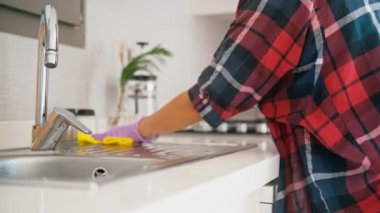 Close-up shot of hands in latex gloves washing kitchen sink