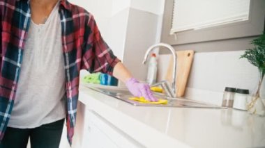 Close-up shot of hands in latex gloves washing kitchen sink