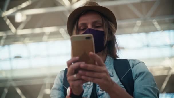 A young woman in a face protective mask using her smartphone — Stock video