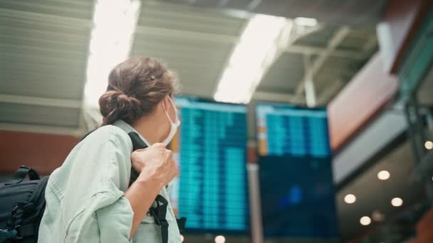 Una giovane donna in maschera che guarda il suo orologio mentre è in aeroporto — Video Stock