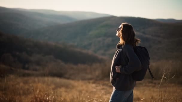 En ung vuxen kvinna njuter av frisk luft och utsikt från kullen medan du vandrar. — Stockvideo