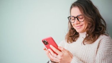 Portrait of a young woman wearing glasses using her smartphone.