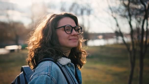 Porträtt av en ung kvinna med ryggsäck i glasögon. — Stockvideo