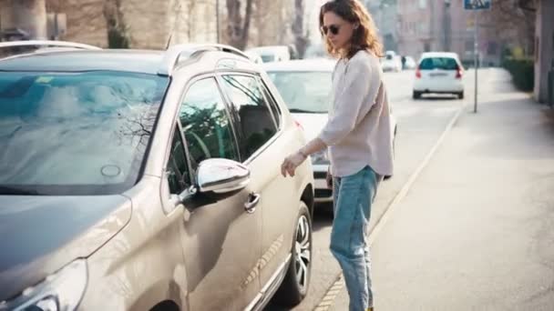 En ung kvinna låser upp en parkerad bil — Stockvideo