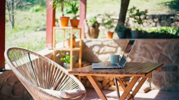 Ordenador portátil en una mesa de madera en una soleada terraza de verano — Vídeos de Stock