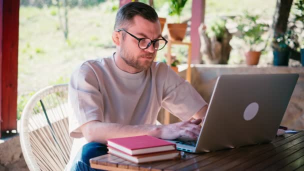 Um jovem recebe más notícias se sente frustrado ao trabalhar no laptop — Vídeo de Stock