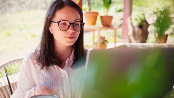 Una joven freelancer recibe una videollamada en su portátil — Vídeo de stock