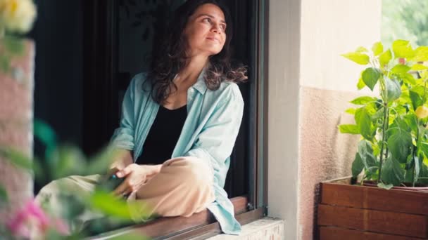 Молода Доросла Жінка Насолоджується Ранком Сидячи Біля Відкритого Вікна Патіо — стокове відео