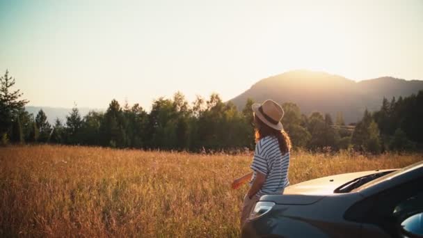Кінематографічні Кадри Молодої Жінки Стоїть Капоті Машини Насолоджується Заходом Сонця — стокове відео