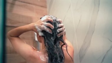 Saçını şampuanla yıkayan genç bir kadının el kamerasıyla çekilmiş bir fotoğrafı.