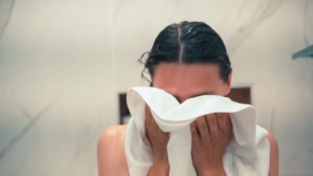 シャワーの後に白いタオルで顔と髪を拭く若い女性のクローズアップショット — ストック動画