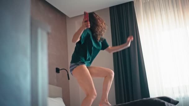 Tânără Caucaziană Veselă Distrează Sărind Dansând Pat Timp Ascultă Muzică — Videoclip de stoc