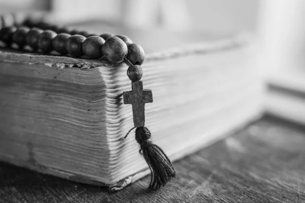 キリスト教の十字架を持つ木製の祈りのビーズは 木製の背景に聖書の本にあります カトリックと正教の概念 — ストック写真