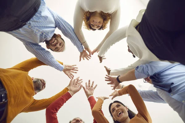 Disparo de ángulo bajo de personas felices y diversas de pie en círculo, uniendo las manos y sonriendo — Foto de Stock