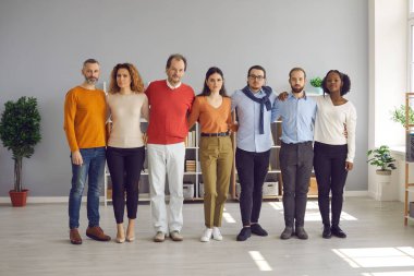 Çeşitli etnik çeşitlilikteki yetişkinler ve gençler sıraya dizilmişler.