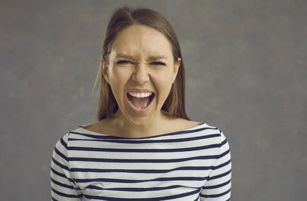 Studio portrait of an angry stressed crazy young woman screaming loudly at the camera — Stock Photo, Image