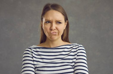 Dudaklarını büzen ve gücenmiş bir yüz ifadesiyle başka yere bakan genç bir kadının portresi.