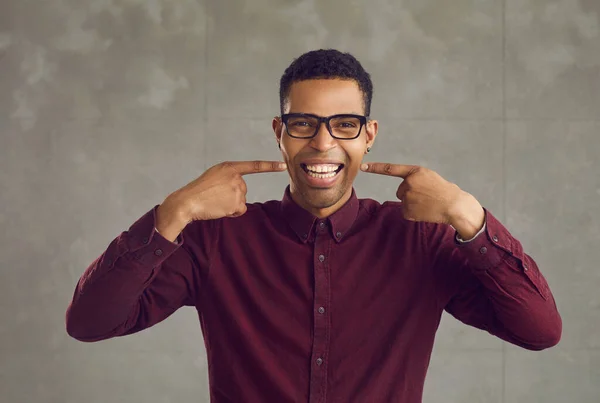 Jonge Afro-Amerikaanse man wijzend met witte tanden glimlach studio schot — Stockfoto