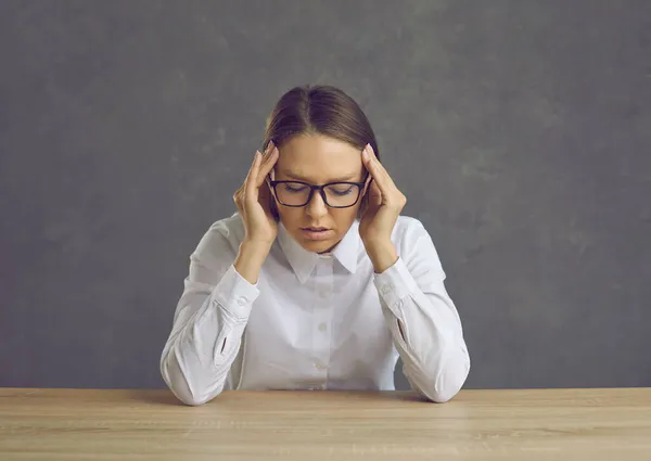 Trabajadora de oficina o maestra cansada que sufre de dolor de cabeza sentada en el escritorio — Foto de Stock