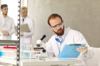 Laboratuvarda test sonuçlarıyla birlikte panoya bakan bilim adamının portresi
