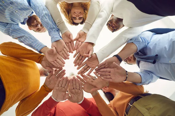 Equipe de homens e mulheres positivamente diversos colocar as mãos juntas, vista de baixo — Fotografia de Stock