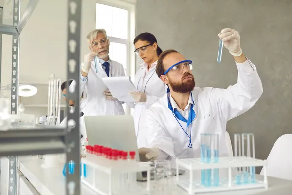 Focus op mannelijke wetenschapper voor laptop met reageerbuiskolf in het laboratorium — Stockfoto