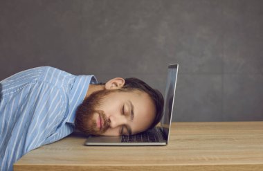 Yorgun iş adamı ofis çalışanı dizüstü bilgisayarda uyuyor.