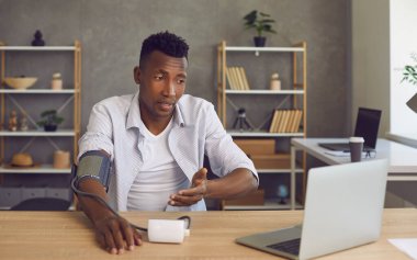 Tansiyon monitörü ve online danışmanlık yapan hipertansiyonu yüksek zenci bir adam.